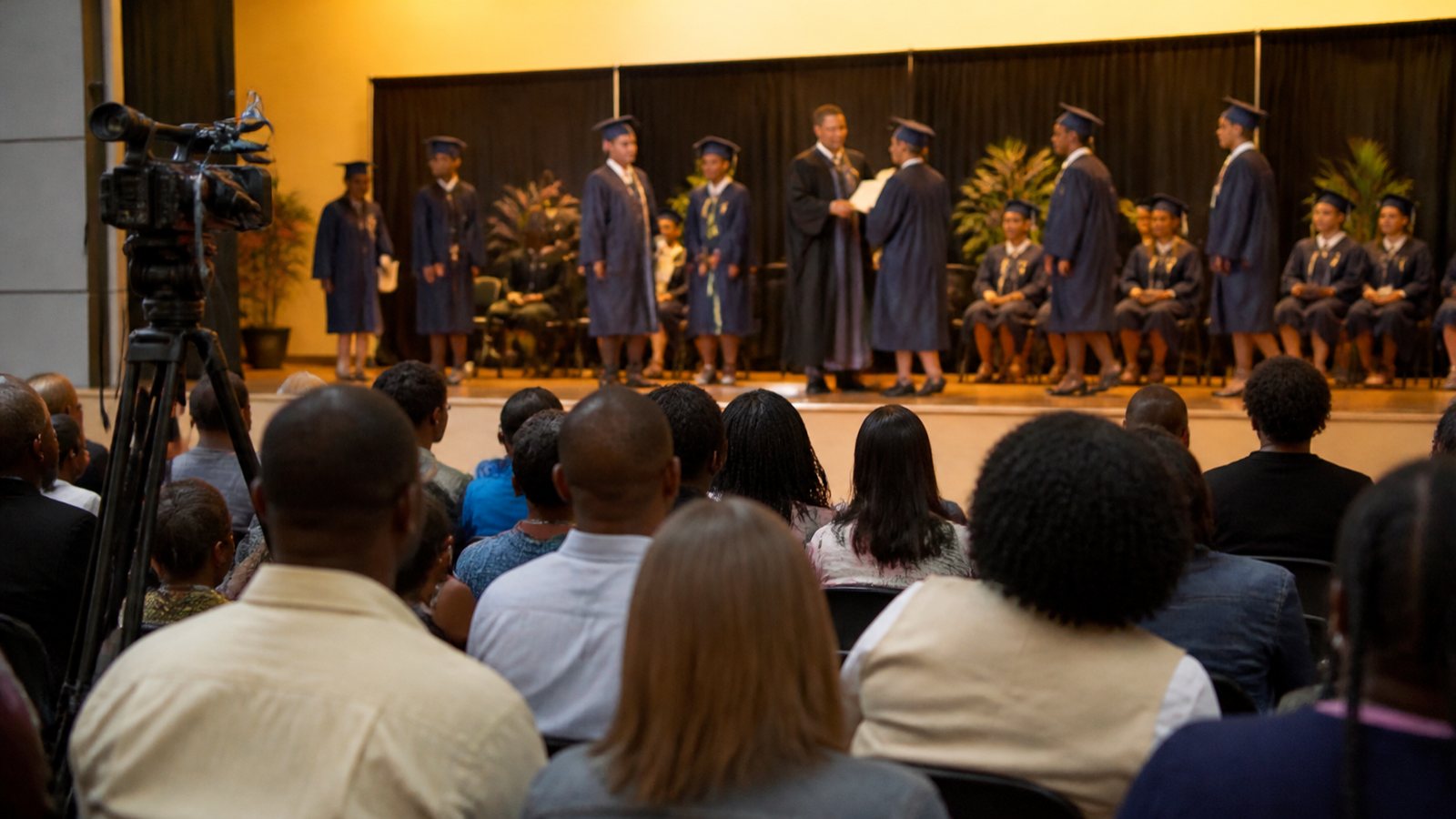 Graduates crossing the stage at a school graduation ceremony